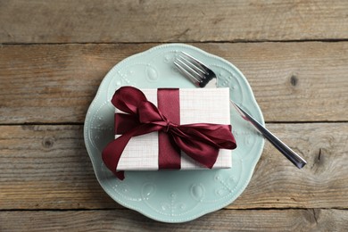 Photo of Beautiful table setting with romantic gift on wooden background, top view