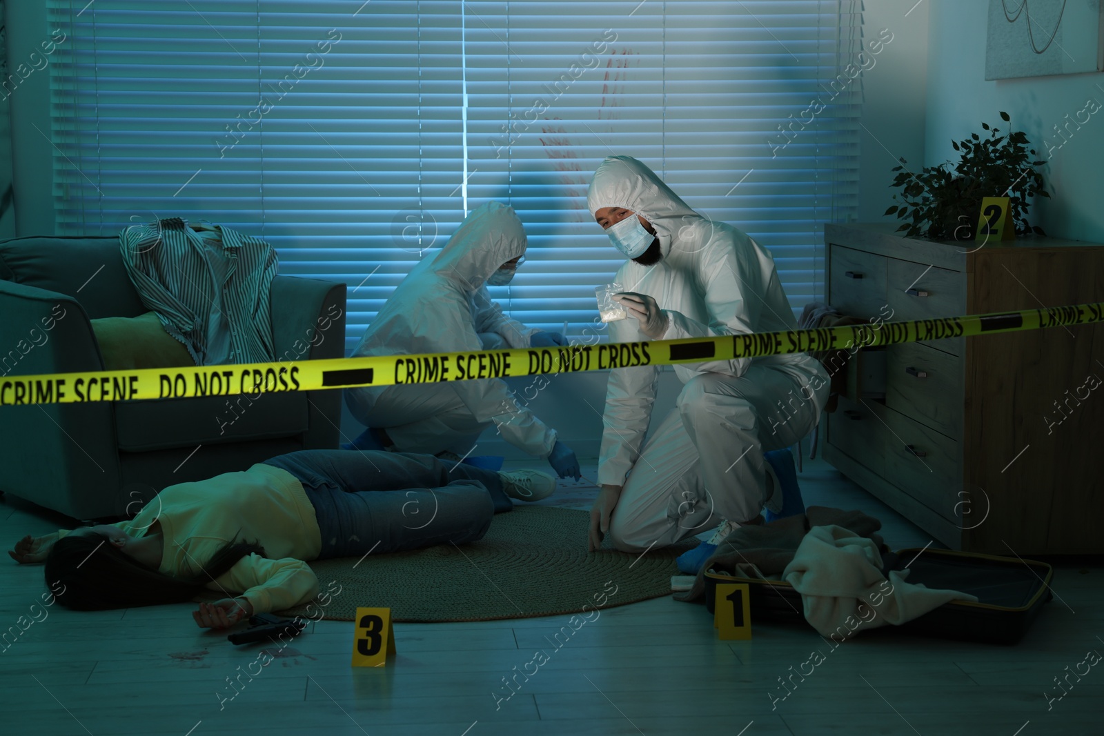 Photo of Forensic experts working at crime scene with dead woman's body indoors