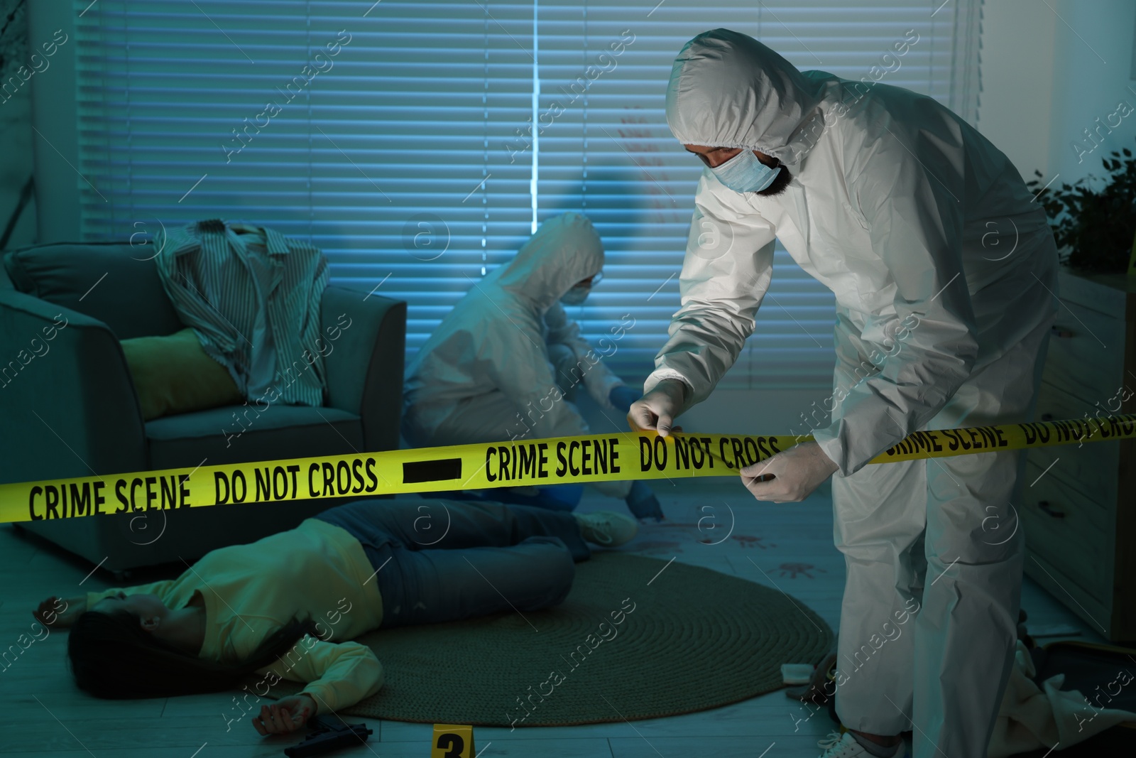 Photo of Forensic experts working at crime scene with dead woman's body indoors