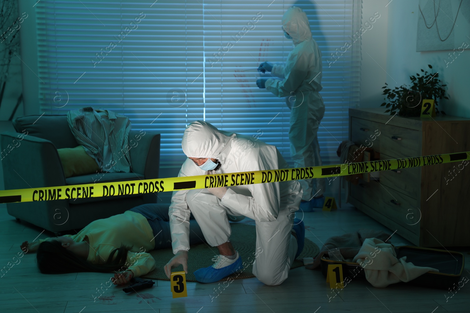 Photo of Forensic experts working at crime scene with dead woman's body indoors