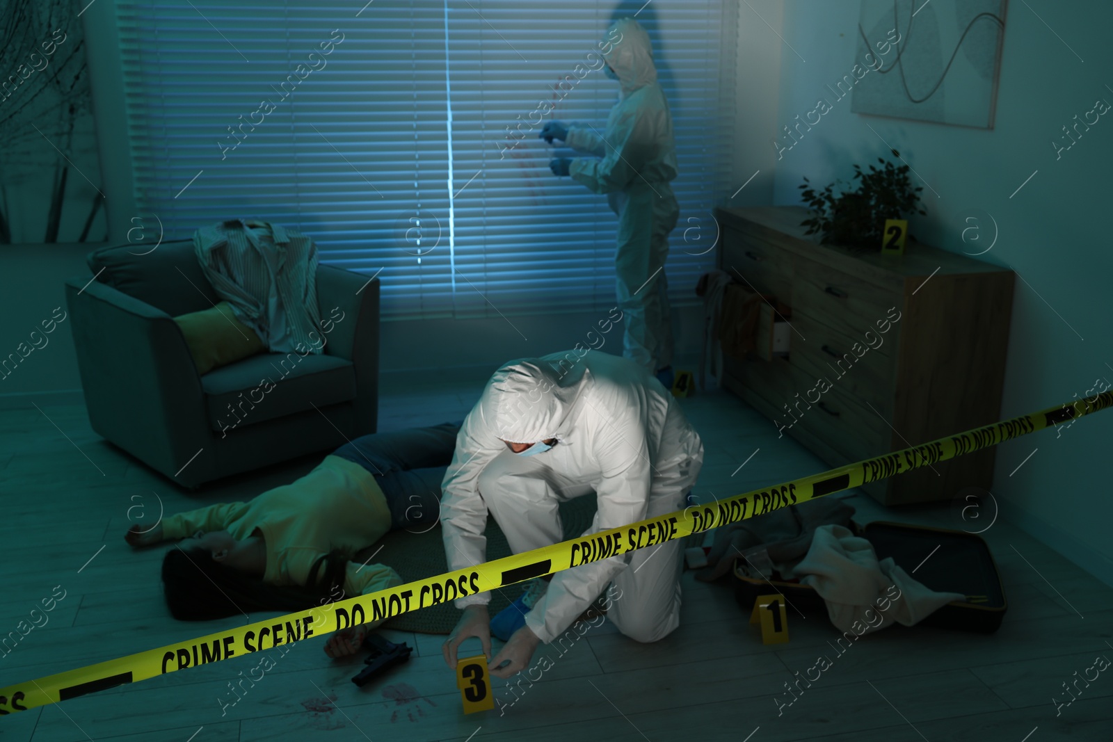 Photo of Forensic experts working at crime scene with dead woman's body indoors