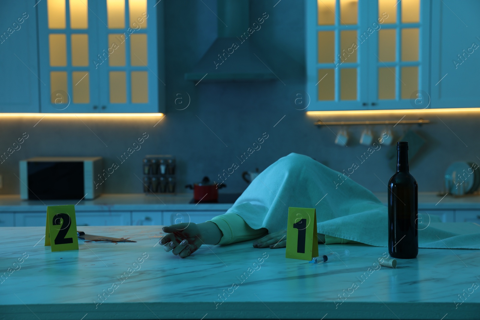 Photo of Dead woman's body, syringe, knife and bottle of wine on marble countertop in kitchen