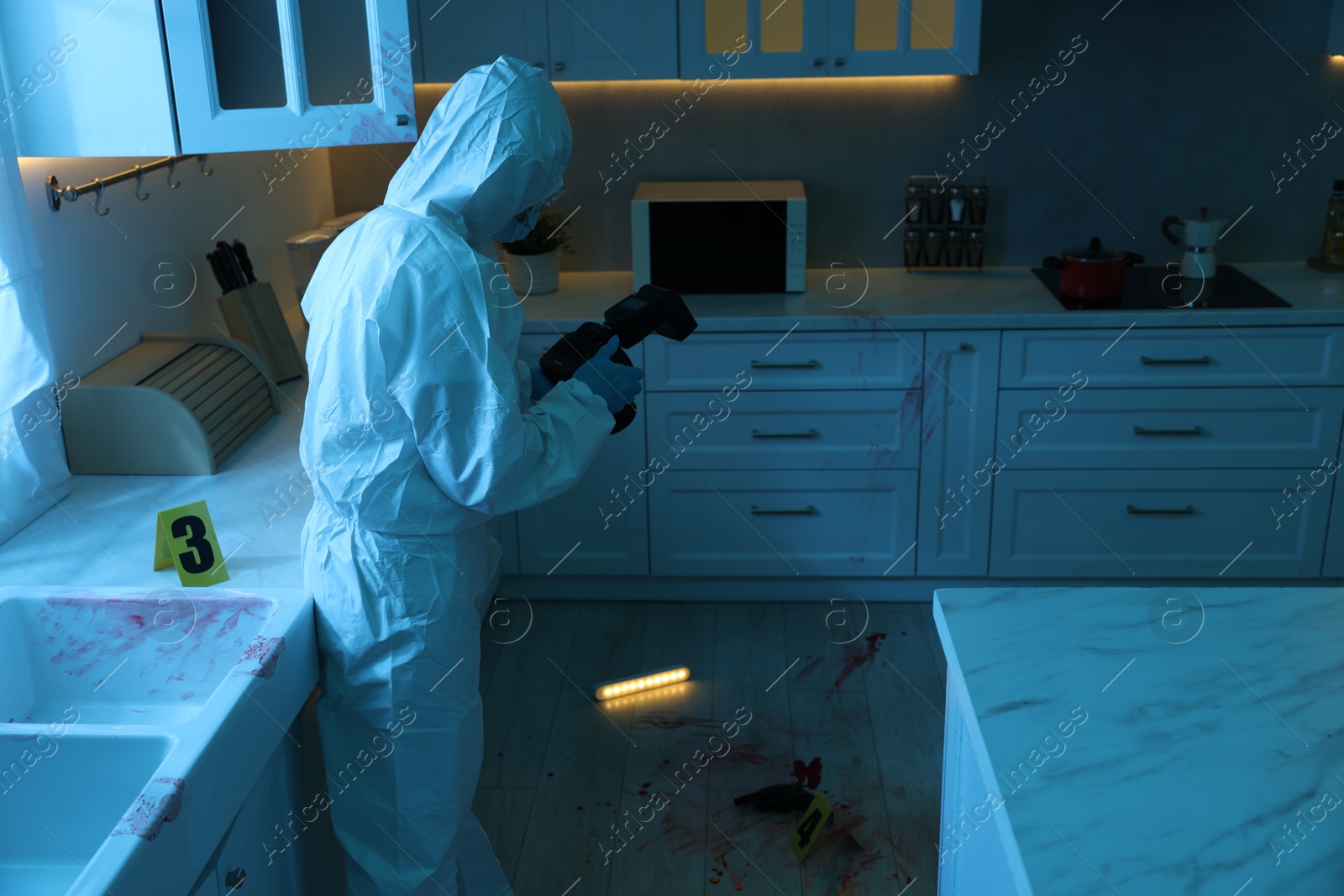 Photo of Forensic expert with camera working at crime scene in dark room