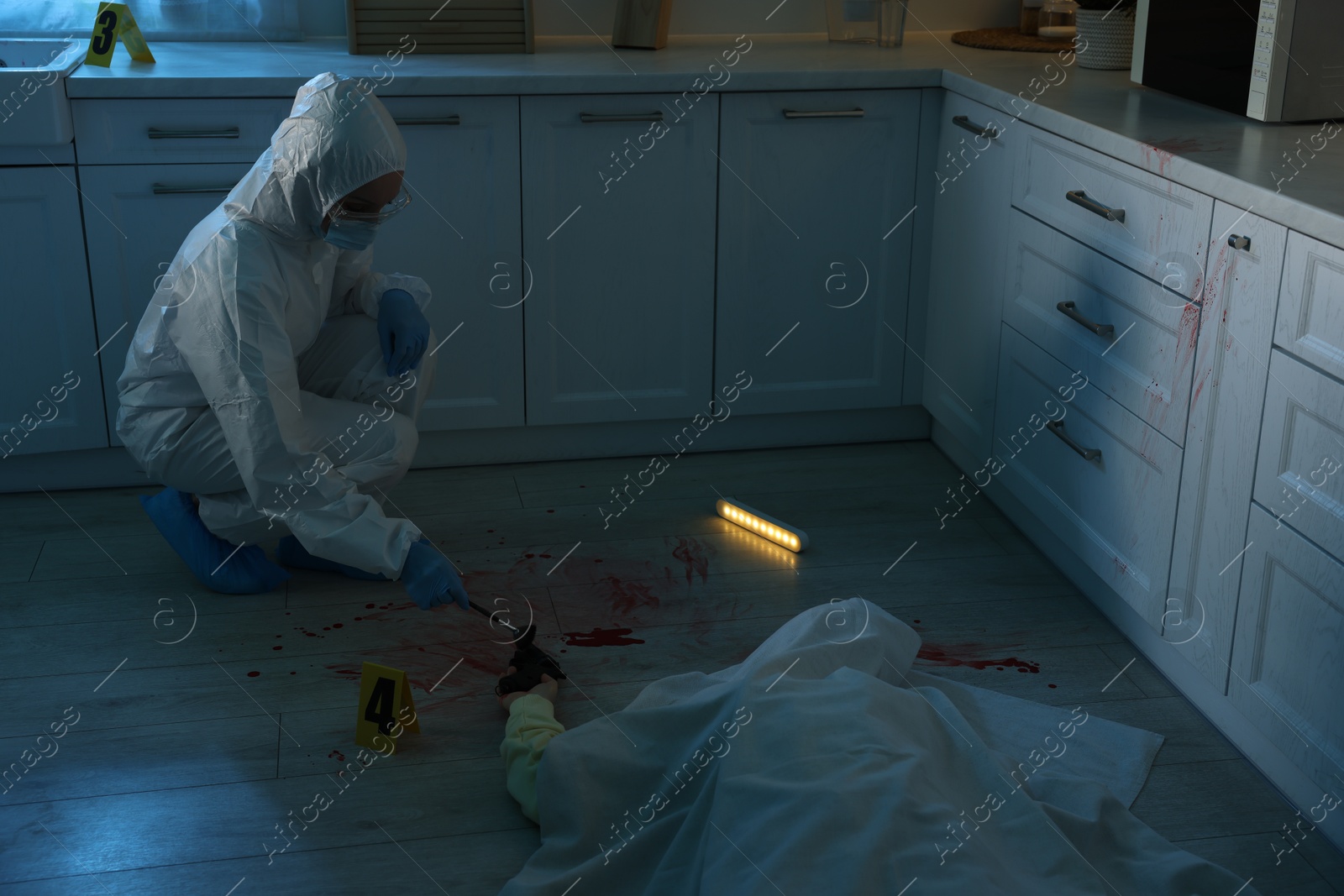 Photo of Forensic expert taking fingerprints with brush from gun and dead body at crime scene indoors