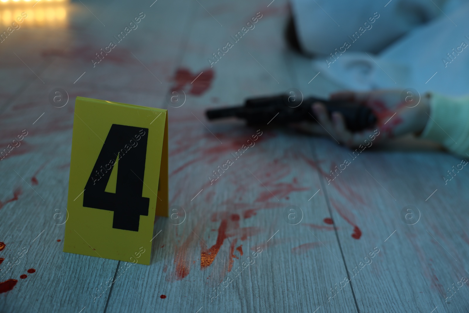 Photo of Dead body with gun at crime scene indoors, focus on numbered marker stand