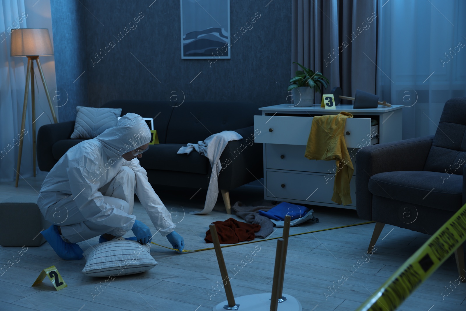 Photo of Forensic expert with measuring tape working at crime scene in messy dark room