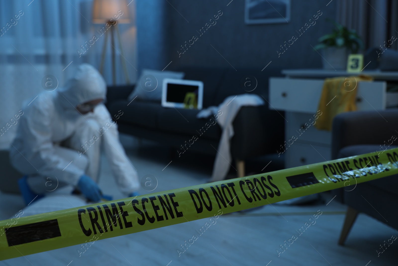 Photo of Forensic expert working at crime scene in messy room, focus on yellow tape