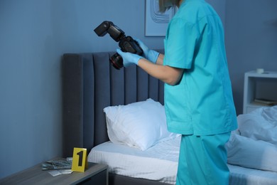 Forensic expert with camera working at crime scene indoors, closeup