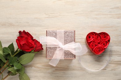 Photo of Romantic gift, roses and buds on light wooden table, flat lay. Happy Valentine's day