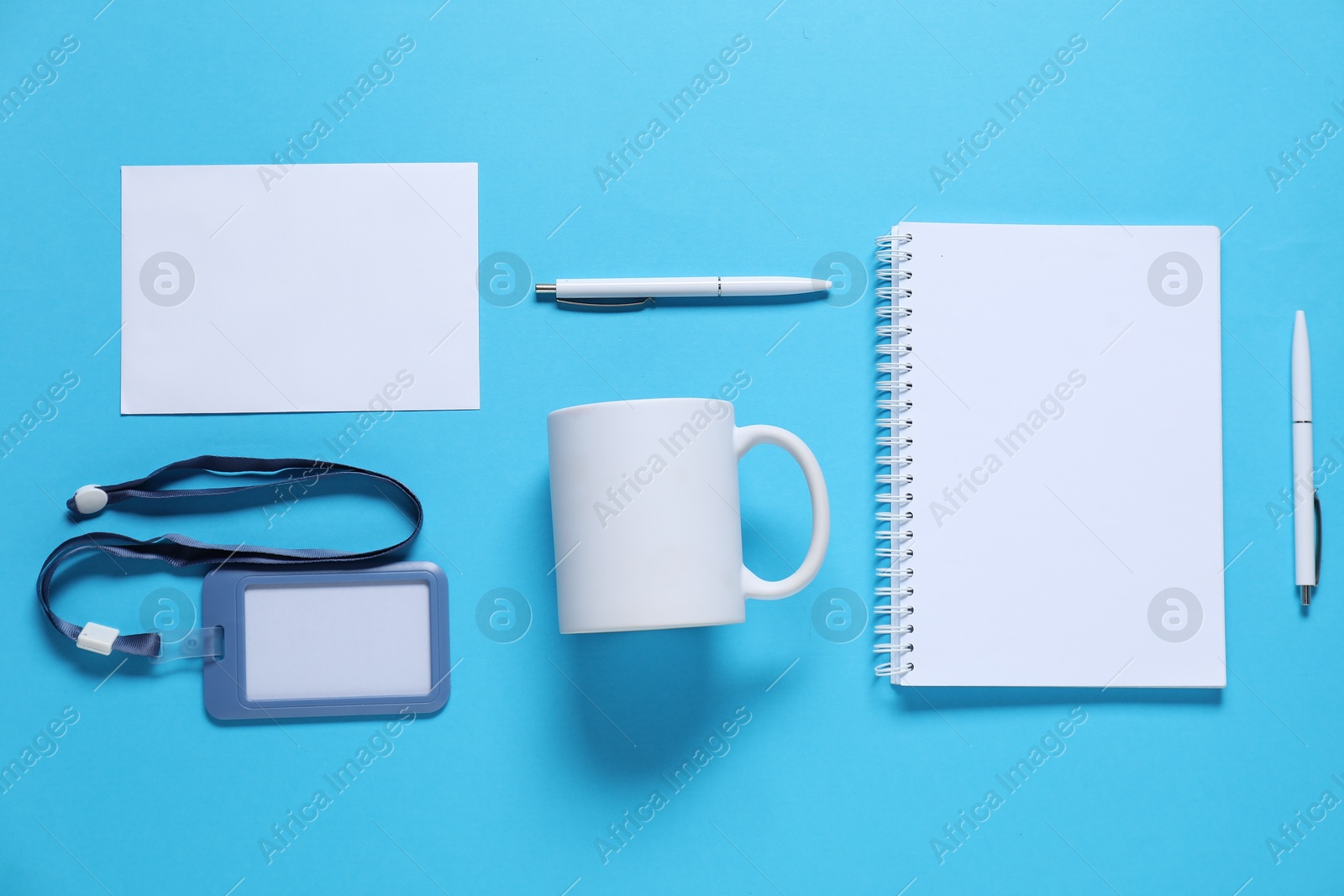 Photo of Different blank items for branding on light blue background, flat lay. Mockup for design