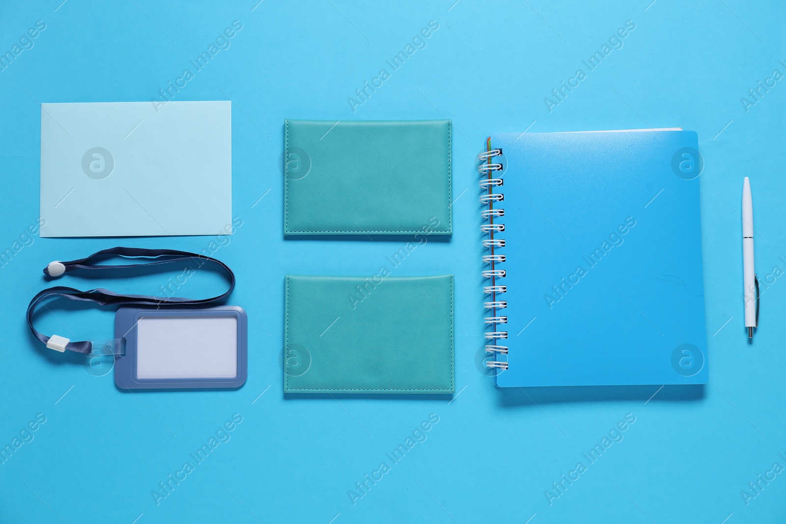 Photo of Different blank items for branding on light blue background, flat lay. Mockup for design