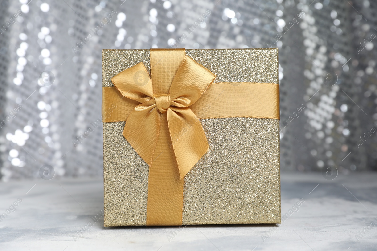 Photo of Romantic gift on table against silver glitter background