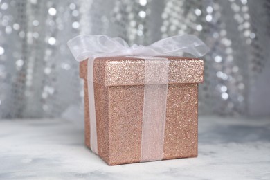 Photo of Romantic gift on table against silver glitter background, closeup