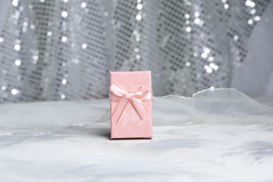 Photo of Romantic gift on table against silver glitter background