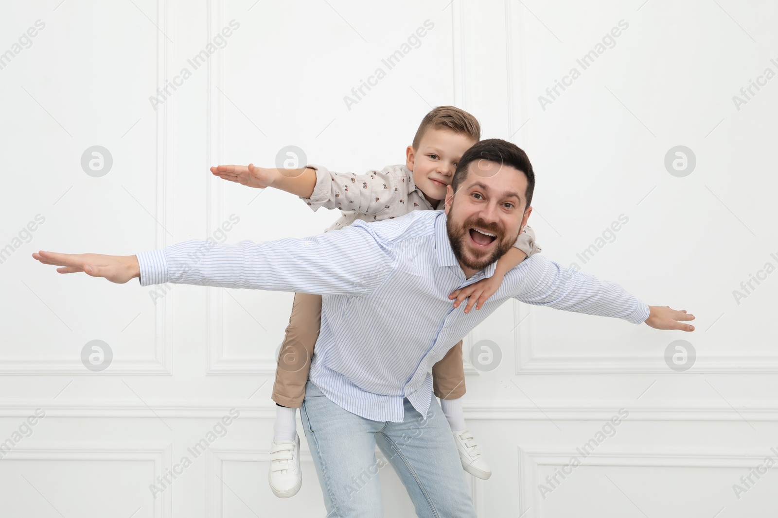 Photo of Happy father and his cute little son near white wall indoors