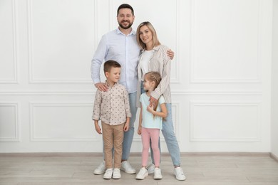 Photo of Happy parents and their children near white wall indoors