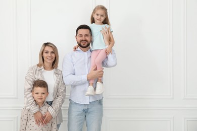 Photo of Happy parents and their children near white wall indoors, space for text