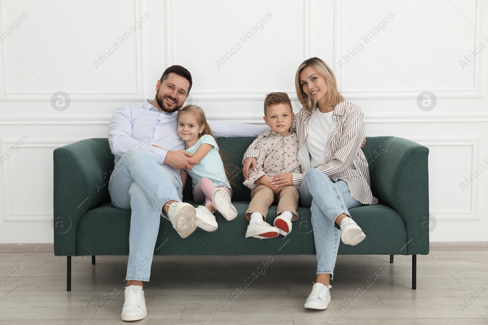 Photo of Happy parents and their children on sofa at home