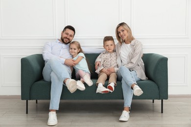 Happy parents and their children on sofa at home