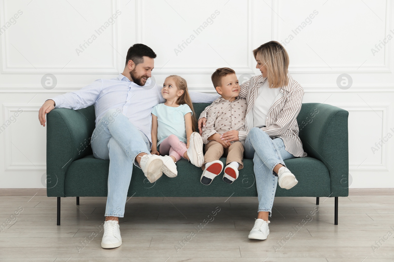 Photo of Happy parents and their children on sofa at home