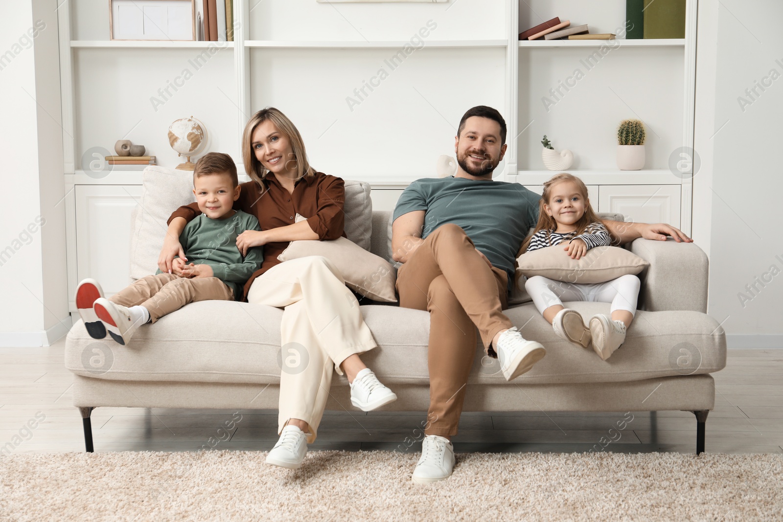 Photo of Happy parents and their children on sofa at home