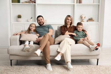 Happy parents and their children on sofa at home