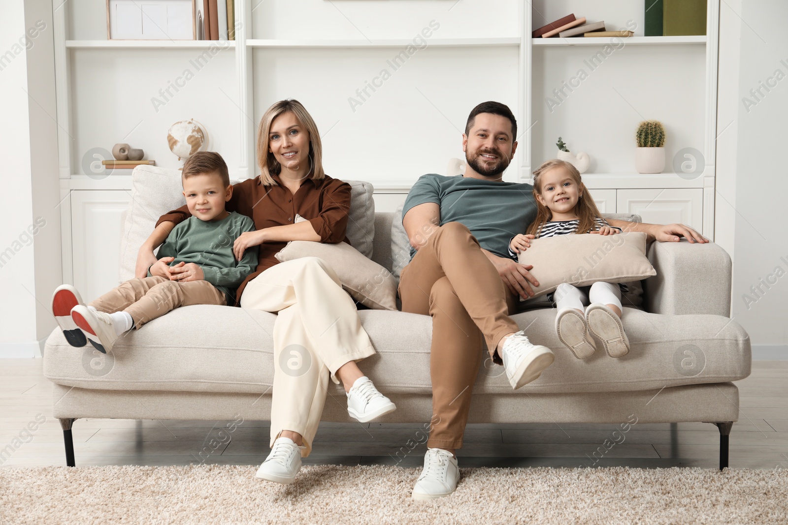 Photo of Happy parents and their children on sofa at home