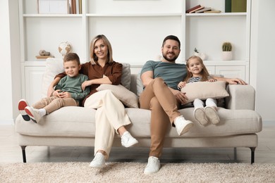 Photo of Happy parents and their children on sofa at home