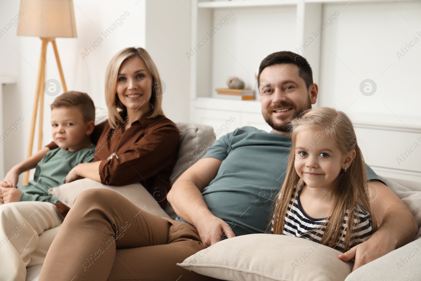 Photo of Happy parents and their children on sofa at home