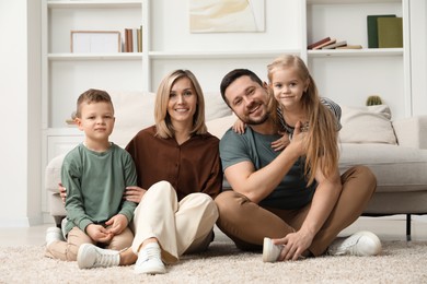 Photo of Happy parents and their children on rug at home