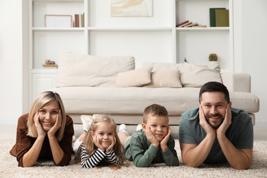 Photo of Happy parents and their children lying on rug at home