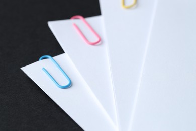 Photo of Paper notes with clips on black table, closeup