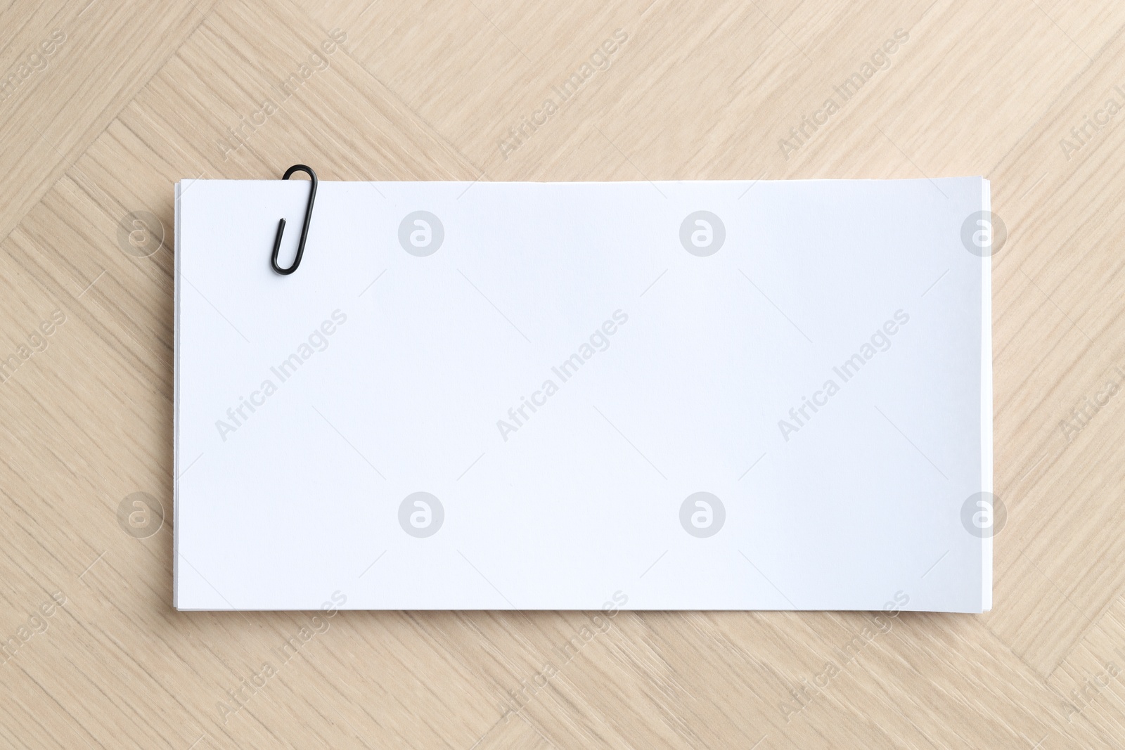 Photo of Paper notes with clip on wooden table, top view. Space for text