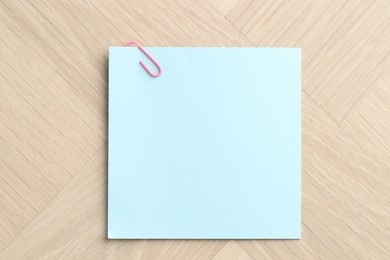 Photo of Paper note with clip on wooden table, top view. Space for text