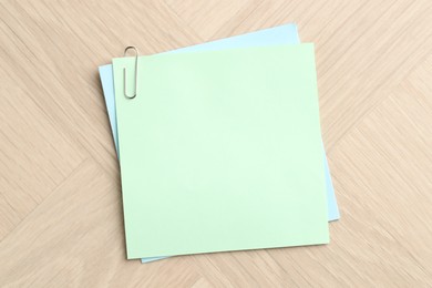 Photo of Paper notes with clips on wooden table, top view. Space for text