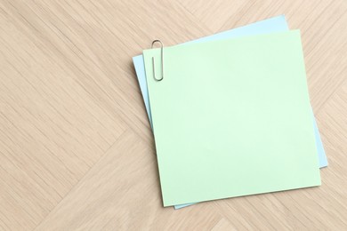 Photo of Paper notes with clips on wooden table, top view. Space for text