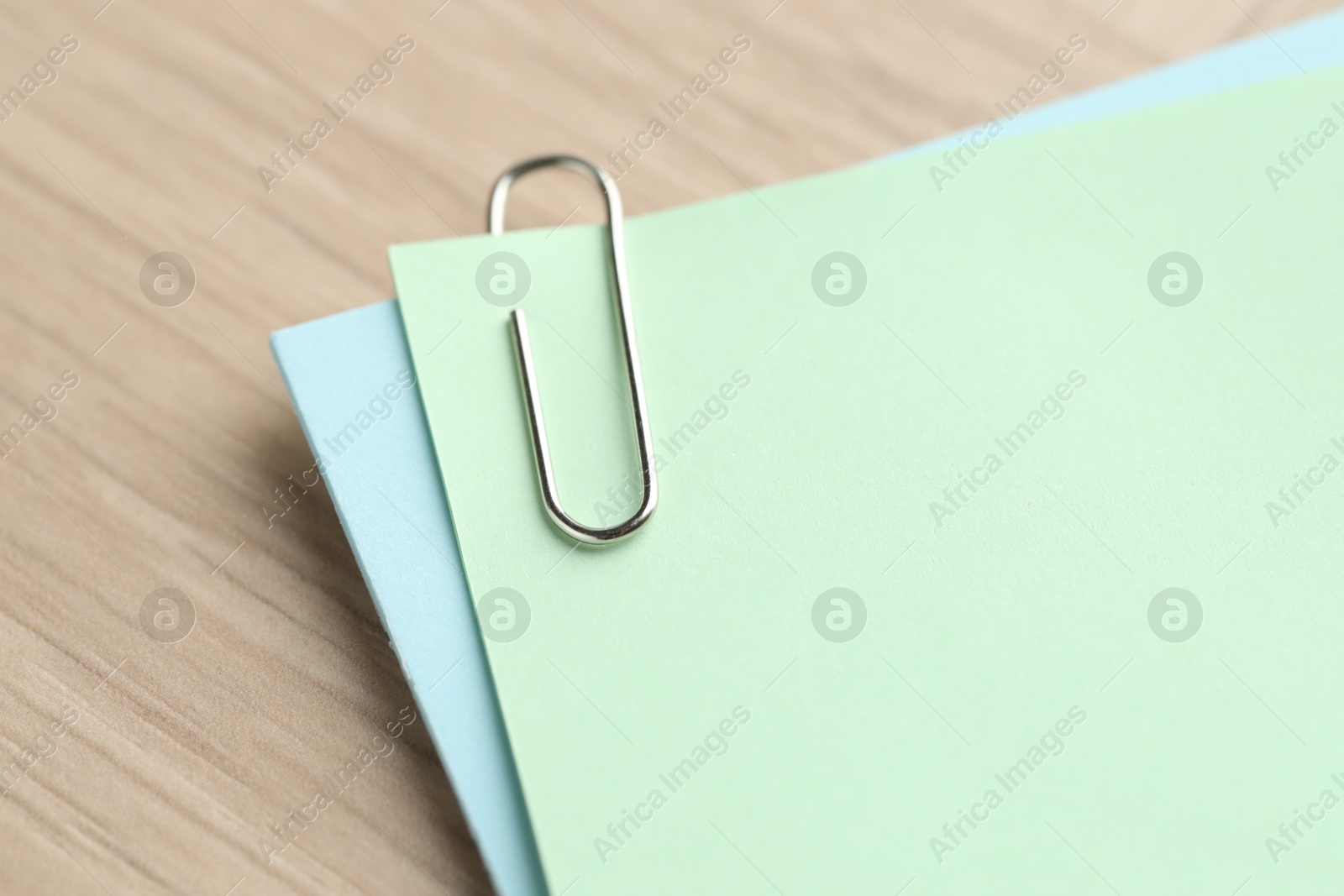 Photo of Paper notes with clips on wooden table, closeup. Space for text