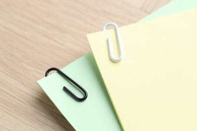 Photo of Paper notes with clips on wooden table, closeup. Space for text