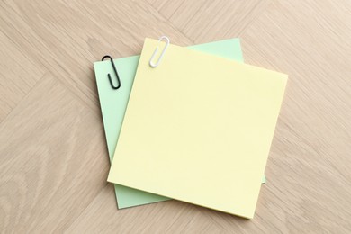 Photo of Paper notes with clips on wooden table, top view. Space for text