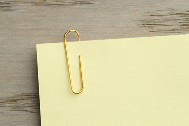 Photo of Paper note with clip on wooden table, top view. Space for text