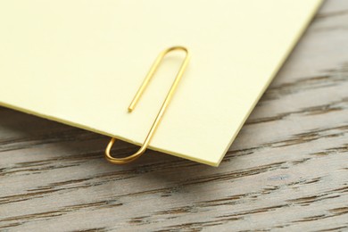 Photo of Paper note with clip on wooden table, closeup