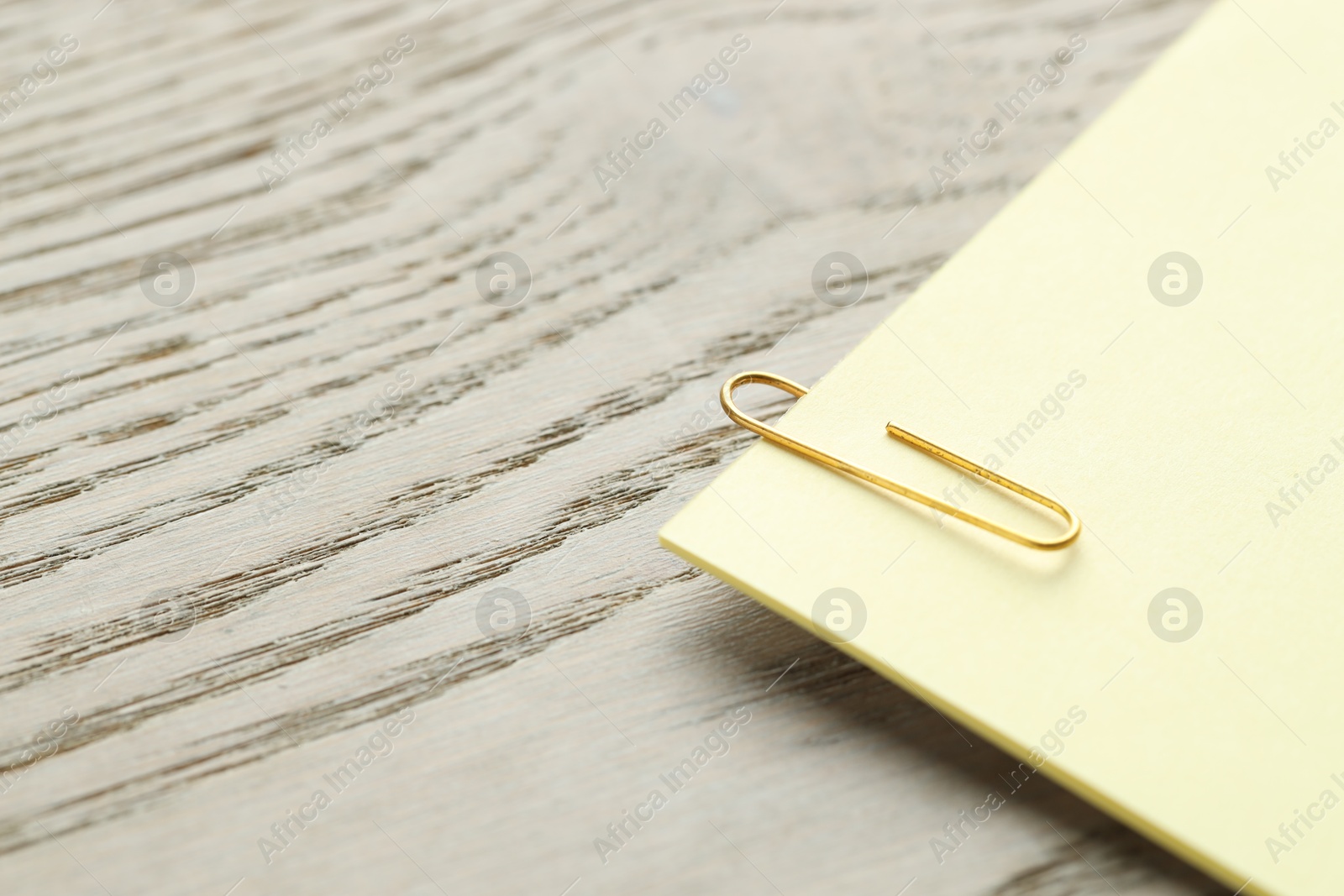 Photo of Paper note with clip on wooden table, closeup. Space for text