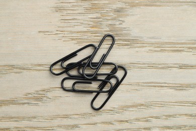 Photo of Many black paper clips on wooden table, top view