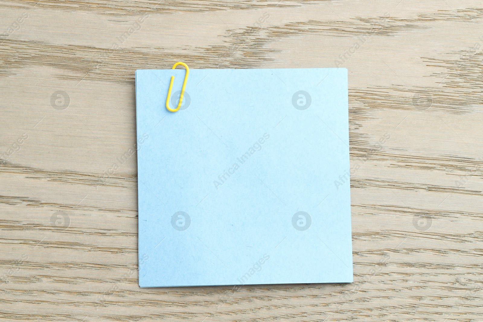 Photo of Paper notes with clip on wooden table, top view. Space for text