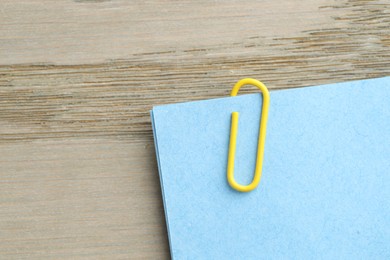 Photo of Paper notes with clip on wooden table, top view. Space for text