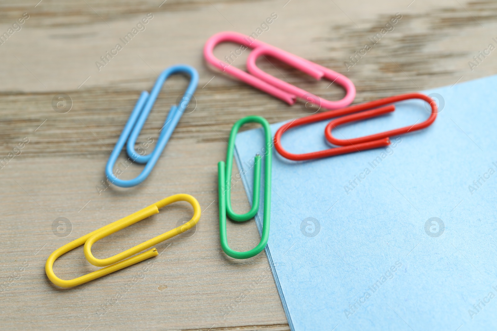 Photo of Many colorful clips and paper notes on wooden table, closeup