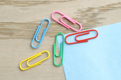 Photo of Many colorful clips and paper notes on wooden table, flat lay