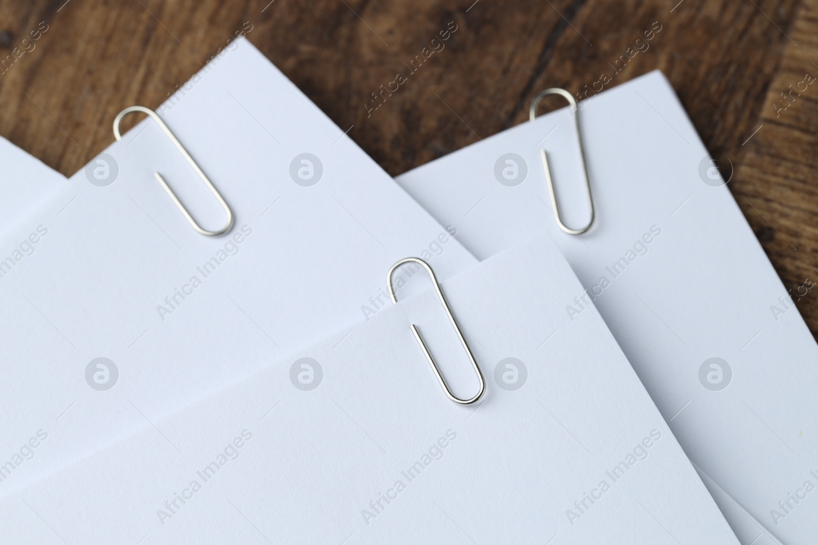 Photo of Paper notes with clips on wooden table, closeup