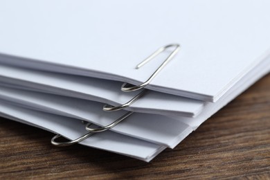 Photo of Paper notes with clips on wooden table, closeup