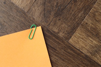 Photo of Paper note with clip on wooden table, top view. Space for text